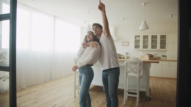 Young couple dreaming new house interior. Family hugging at kitchen.