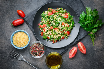 Traditional oriental salad Tabbouleh with bulgur and parsley on a dark background top view.