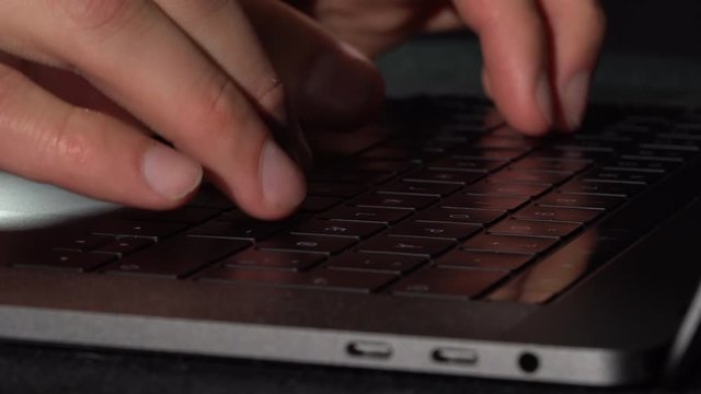 Person Writing on laptop keyboard, static low-key close up