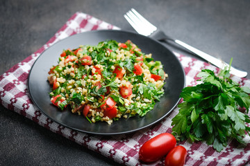 Traditional oriental salad Tabbouleh with bulgur and parsley on a dark background