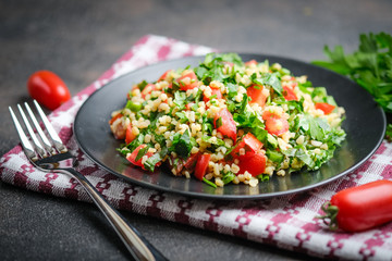 Traditional oriental salad Tabbouleh with bulgur and parsley on a dark background