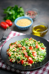 Traditional oriental salad Tabbouleh with bulgur and parsley on a dark background
