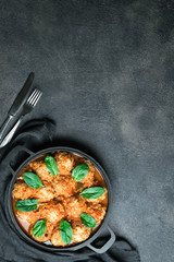 Meatballs in a pan with spinach leaves on a dark background copy space. Top view.