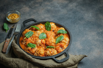 Meatballs in a pan with spinach leaves on a dark background copy space.