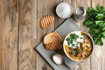 Homemade soup with porcini mushrooms croutons and herbs on a light wooden background top view.