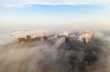 Aerial view. Pipes Throwing Smoke in the Sky. Large Plant on the Background of the City.