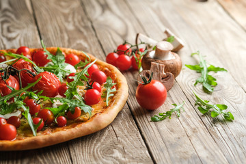 Traditional italian pizza with cherry tomatoes on a wooden shovel on a dark background.