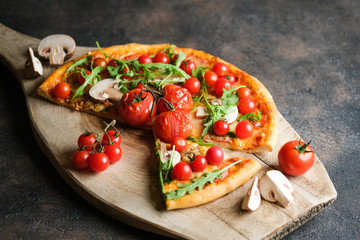 Traditional italian pizza with cherry tomatoes on a wooden shovel on a dark background.