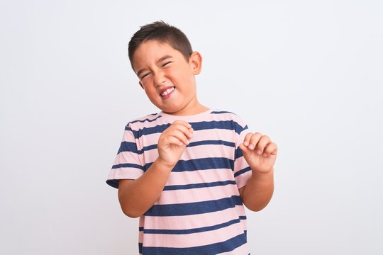 Beautiful kid boy wearing casual striped t-shirt standing over isolated white background disgusted expression, displeased and fearful doing disgust face because aversion reaction. With hands raised.