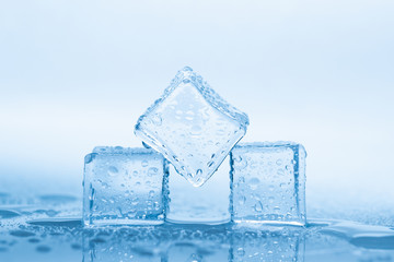 Ice three cubes with drops water clean on blue background