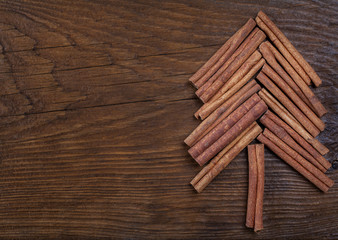 Christmas card with fir tree made from spices cinnamon sticks, anise star on rustic wooden background. Celebration concept. Place for text, Flat lay, top view, copy space