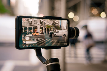 Man using phone with stabilizer and taking pictures and live video in New York city. Vlog, video blogging, street photography concept. - 303155350
