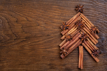 Christmas card with fir tree made from spices cinnamon sticks, anise star on rustic wooden background. Celebration concept. Place for text, Flat lay, top view, copy space