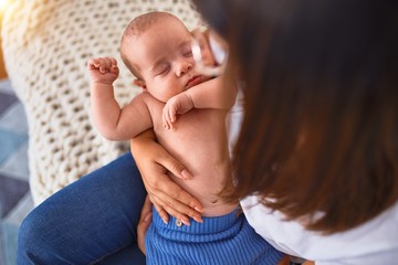 Young beautifull woman and her baby on the sofa over blanket at home. Newborn and mother relaxing and resting comfortable
