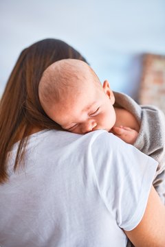 Young beautifull woman and her baby standing on the floor at home. Mother holding and hugging her son sleeped