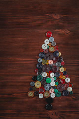 Handmade Christmas tree made of colorful sewing buttons over wooden vintage background with copy space. Spring time tree. Abstract. Holidays concept