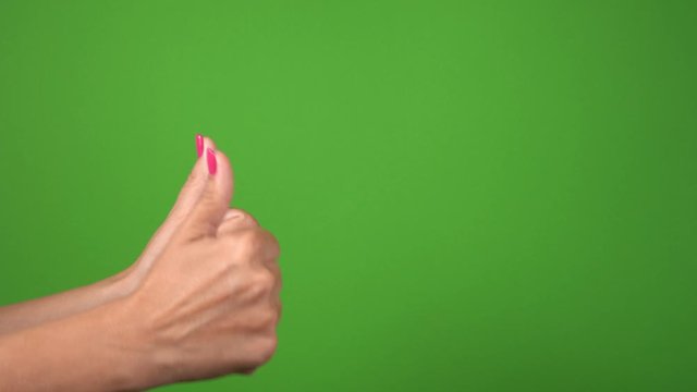 Close up side view of beautiful two female hands isolated on green background. Woman showing thumbs up happily and cheerfully. Real time 4k video footage.