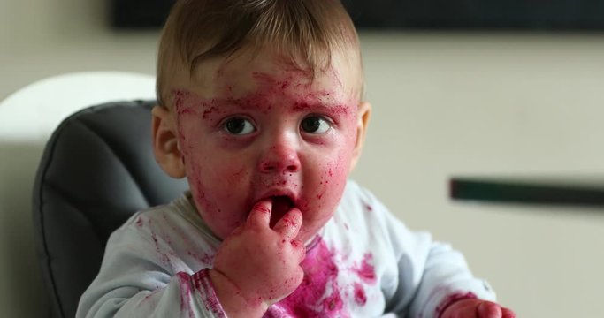 Funny infant baby covered with beet red sauce after eating mess