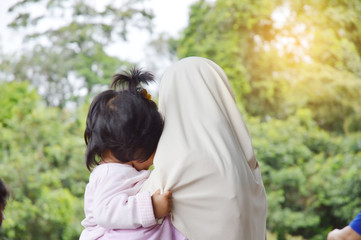 An Islamic mother holds her child and holds her mother's robe tight.