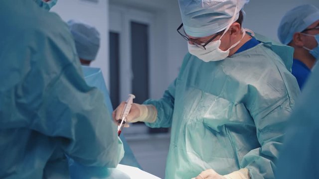 Operation bone marrow transplant. Group of surgeons in operating room with surgery equipment. Plasma in syringe.