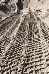Naklejka premium Earth mover tire tracks in sand quarry