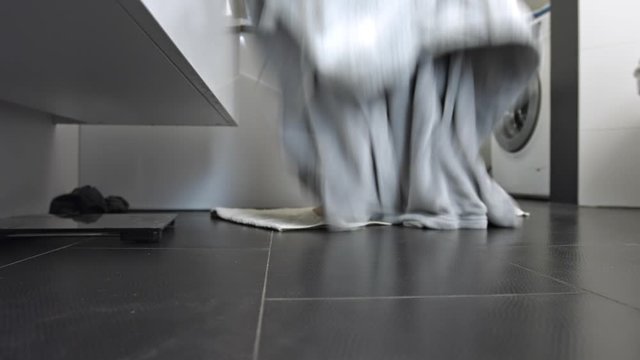 The woman drops her bathrobe and goes into the bathtub to take a bath.