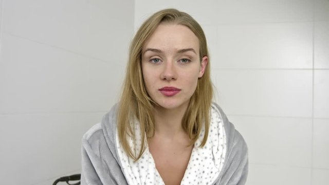 Serious woman in bathroom looking to camera.