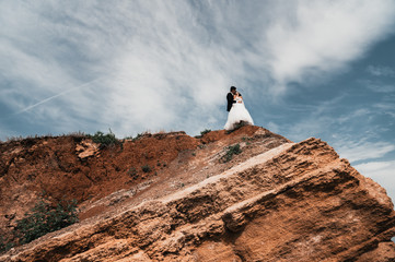  Loving newlyweds stand on a cliff by the ocean
