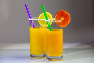 a glass of orange juice with a straw and orange