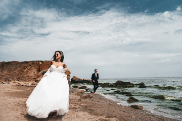  Loving newlywed couple running with a smile along the ocean
