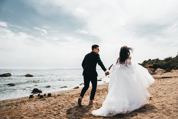  Loving newlywed couple running with a smile along the ocean