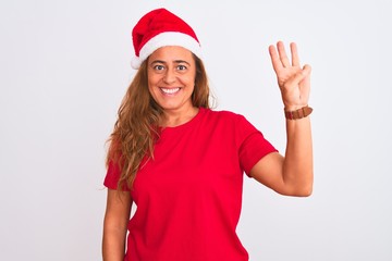 Middle age mature woman wearing christmas hat over isolated background showing and pointing up with fingers number three while smiling confident and happy.