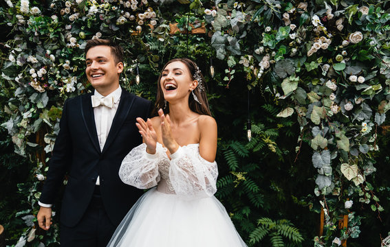 Loving couple of newlyweds rejoice at their wedding day on the background of their photo zone