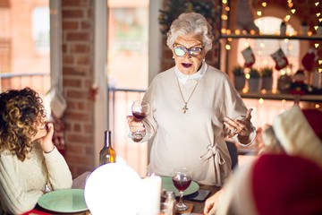 Beautiful group of women smiling happy and confident. On of them holding cup of wine speaking speech celebrating christmas at home