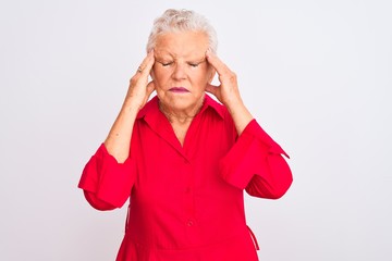 Senior grey-haired woman wearing red casual shirt standing over isolated white background with hand on head for pain in head because stress. Suffering migraine.