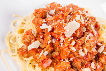 Spaghetti bolognese sprinkled with parmesan on a plate on a white background	