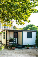 Small white bungalow on campsite. Many trees and alley on camping.