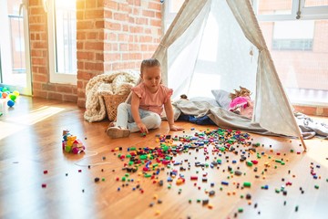Beautiful blond toddler girl playing with constuction blocks outside tipi at kindergarten © Krakenimages.com