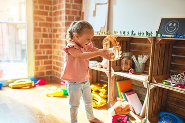 Beautiful blond toddler girl holding princess crown standing at kindergarten