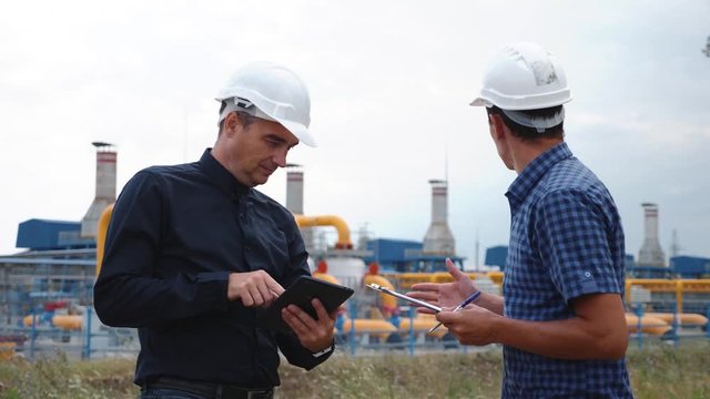 Teamwork. Two helmeted engineers are testing the operation of a gas processing plant. Teamwork Success and Victory Concept