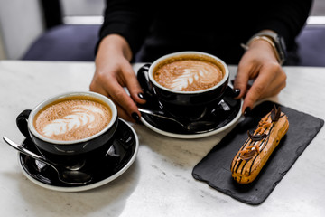 two cups of cappuccino and donut in cafe on white table