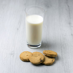 Chocolate homemade pastry cookies on a bright wooden table and a glass of milk