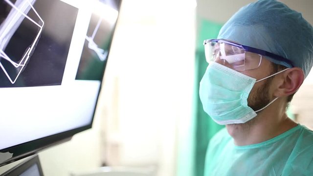 surgeon examines fluorography images on a monitor in an operating room of a medical office.