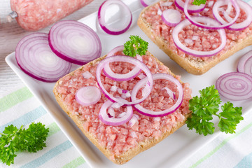 german sandwich mettbrotchen ground pork, bun and raw meat with onion and parsley, closeup