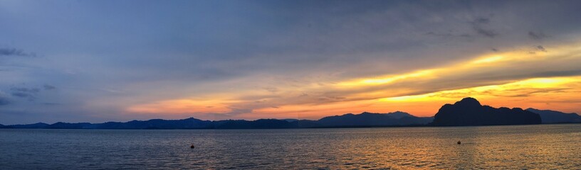 Naklejka na ściany i meble Islands Sunset, Ocean panorama views near Phuket with deep Red, Orange, Purple and Blue, mountains, twilight in Thailand. Including Phi Phi, Ko Rang Yai, Ko Li Pe and other islands. Asia.