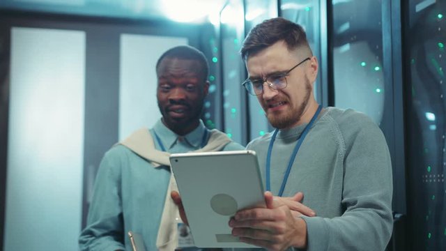 Team of funny server administrators screwed up faces showing disgusting grimaces while browsing tablet content in server room. Data center. Fun concept.