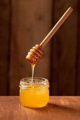 jar with honey on a wooden background with a spoon