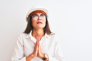 Young beautiful architect woman wearing helmet and glasses over isolated white background begging...