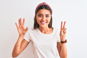 Young beautiful woman wearing casual t-shirt and diadem over isolated white background showing and pointing up with fingers number seven while smiling confident and happy.