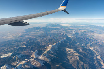 Looking out the window of an airplane soaring high above the scenic vista of the Rocky Mountains in the United States.